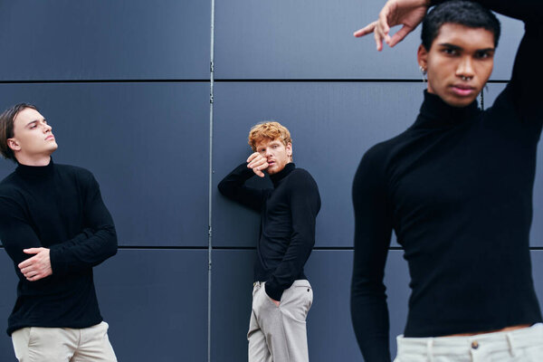good looking interracial group of men posing next to wall in casual black turtlenecks, fashion