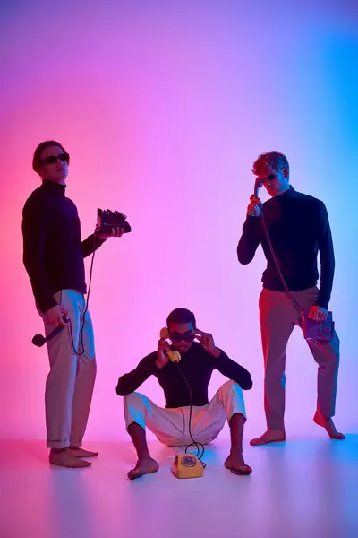 stock image vertical shot of interracial trio encircled by neon lights talking on landline phones, men power