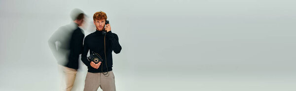 stylish man in elegant turtleneck with landline phone with other man moving, long exposure banner