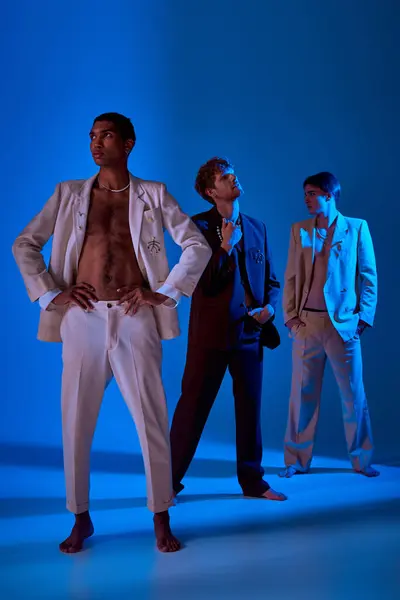 Stock image vertical shot of african american man in unbuttoned suit with other male models posing on backdrop