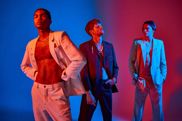 stock image good looking elegant trio in classy suits with accessories with neon lights on faces, men power