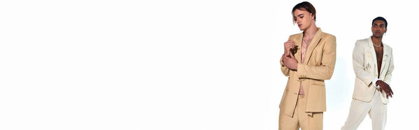 handsome diverse male models in unbuttoned suits posing on white backdrop looking away, banner