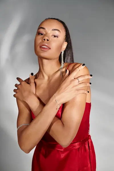 鏡の灰色の背景にポーズするときに腕を交差する赤い服の華やかなアフリカ系アメリカ人女性 — ストック写真
