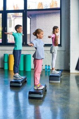 Spor giyimli üç ergen kız ve erkek. Spor kıyafetleri içinde spor ayakkabıları giyiyorlar.