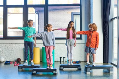 four little cute children in sportswear stretching arms standing fitness steppers, child sport clipart