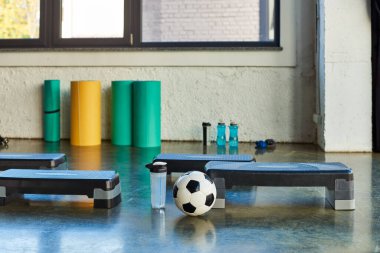 Futbol topu ve su şişesinin fotoğrafı spor konsepti fitness stepper 'ın yanında.