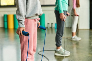 cropped view of three preadolescent children holding skipping ropes in hands in gym, child sport clipart