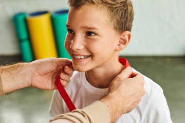 cropped man awarding cheerful preadolescent boy with golden medal, child sport winner clipart