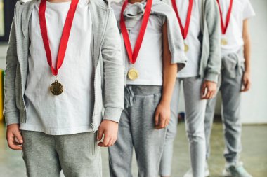 Boyunlarında altın madalyalar olan dört çocuk spor giyim kuşamı manzarası, çocuk sporu.