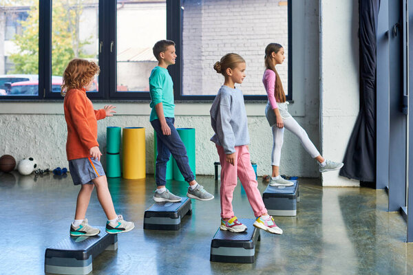 cute boys and girls in sportswear exercising on fitness stepper, raised leg, child sport