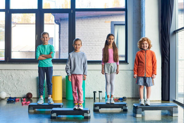 cute preadolescent children standing on fitness steppers and smiling at camera, child sport