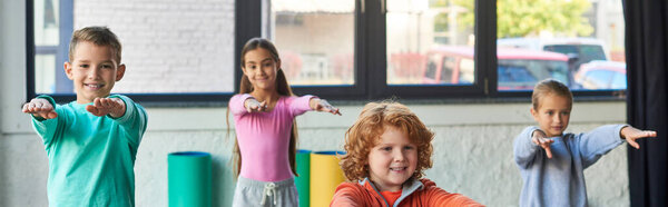 cheerful cute kids stretching with hands in front of them, smiling at camera, child sport, banner