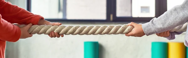 stock image cropped view of two children in sportswear pulling fitness rope in gym, child sport, banner