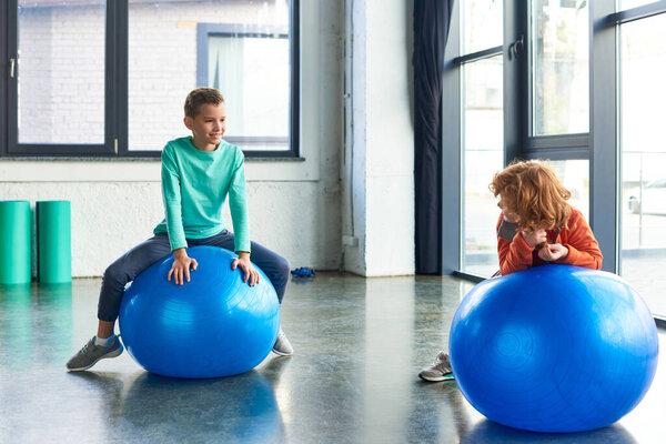 two preadolescent cute boys in sportswear exercising actively on fitness balls, child sport