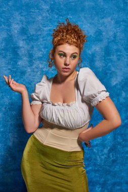 confused plus size model with red wavy hair standing with hands on hip on blue textured backdrop clipart