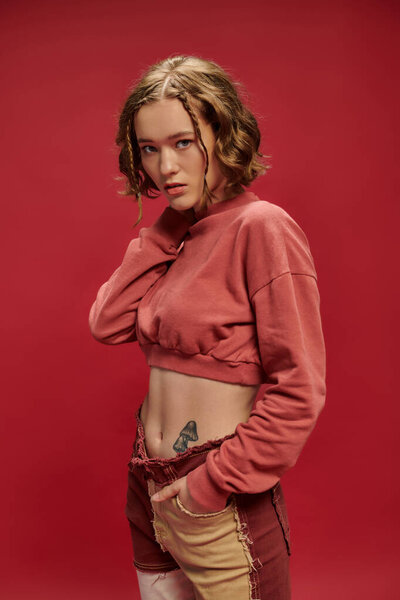 личный стиль, красивая девушка в лоскутных штанах и обрезанный длинный рукав позируя с рукой на шее