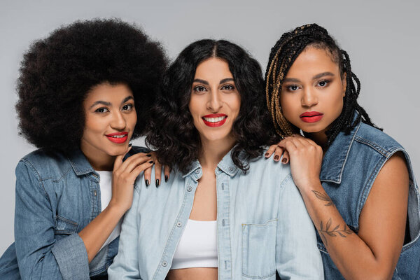 joyful multiracial woman looking at camera near african american girlfriends, denim fashion