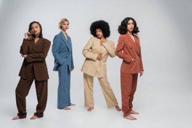 Gri renkte takım elbiseli, çıplak ayaklı kadın arkadaşlarla dolu.