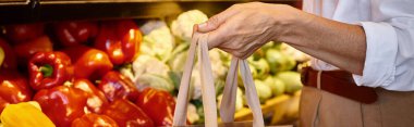 Markette, pankartta, elinde alışveriş poşeti olan, gündelik giyinmiş olgun bir kadın görüntüsü.