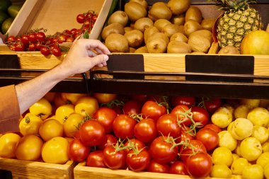 Olgun bir erkek satıcının market tezgahına meyve ve sebzelerle fiyat etiketi yapıştırması.