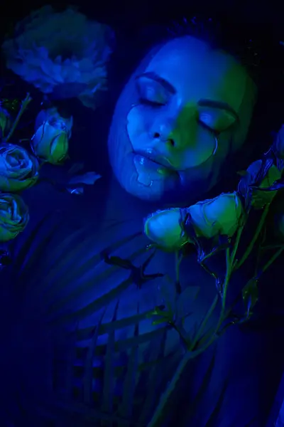 feminine beauty, relaxed young woman lying among palm leaves and flowers in water, dive