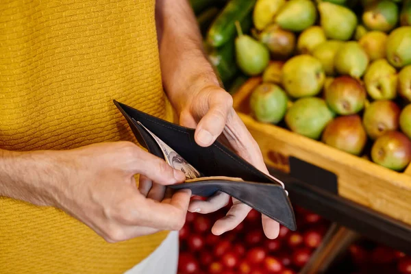 stock image cropped view of mature male customer holding his wallet in hands ready to pay at grocery store