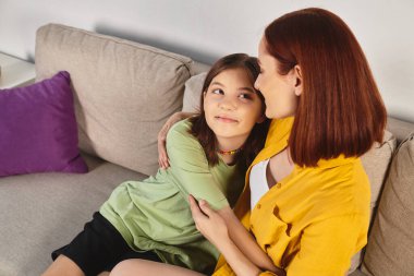 Genç kızı olan neşeli bir kadın oturma odasındaki rahat kanepede sarılıp birbirine bakıyor.