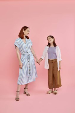 Ergen kızı olan mutlu bir kadın. El ele tutuşup birbirlerine pembe gözleriyle bakıyorlar.