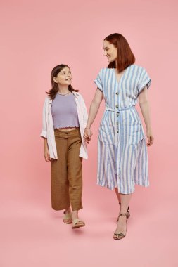 Uzun boylu, neşeli ve şık bir kadın. Küçük kızı var. El ele tutuşuyor ve pembe üzerinde yürüyor.