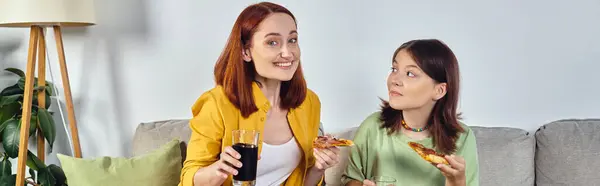 stock image cheerful mother and teenage daughter with pizza and soda on cozy couch in living room, banner