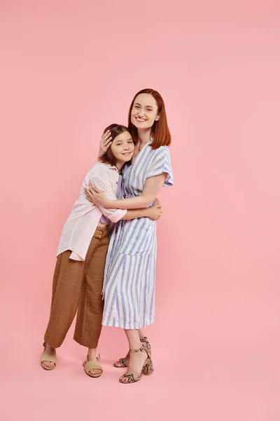 stock image full length of stylish and joyful woman with teen daughter embracing on pink backdrop, happy family