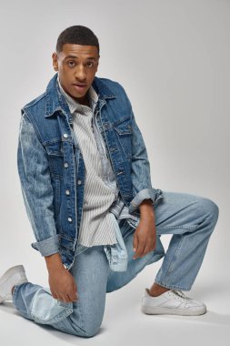 Beyaz arka planda poz veren kot giysili yakışıklı Afrikalı Amerikalı adam, moda konsepti.