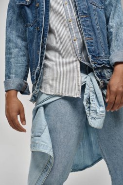Moda konsepti, modaya uygun kot giyip poz veren Afro-Amerikan erkek modelinin kırpılmış görüntüsü.