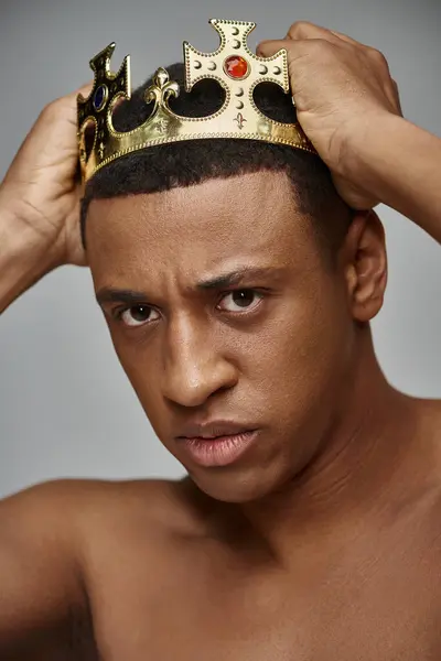 stock image alluring young african american man posing topless with hands on golden crown, fashion concept