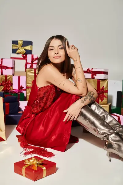 stock image joyous lady sitting on floor surrounded by presents and looking at camera, holiday gifts concept