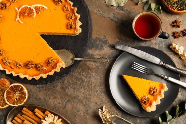 thanksgiving pumpkin pie near vintage cutlery and warm tea on decorated stone table, autumnal theme clipart