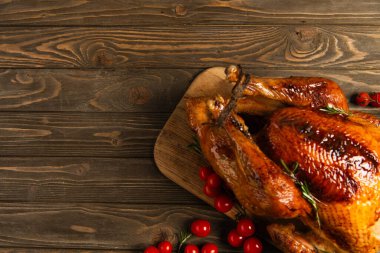 thanksgiving dinner, delicious roasted turkey near ripe red cherry tomatoes on rustic wooden table clipart