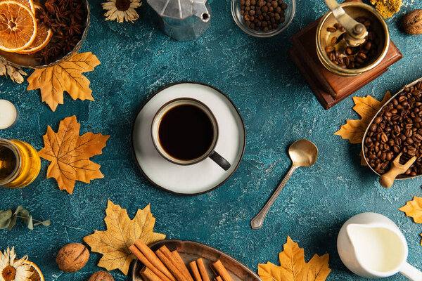 thanksgiving still life, coffee cup on blue textured tabletop with maple leaves and autumnal decor
