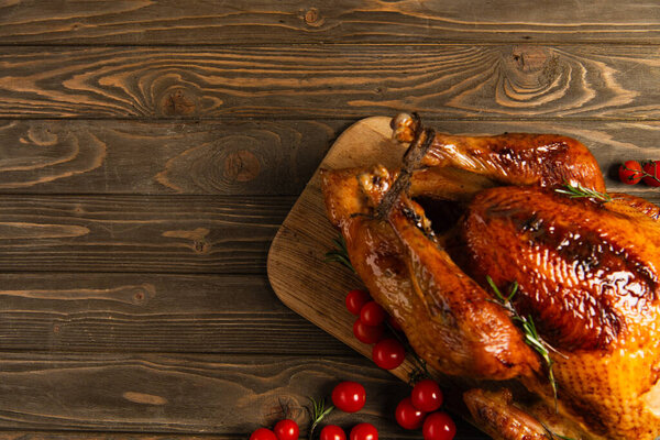 thanksgiving dinner, delicious roasted turkey near ripe red cherry tomatoes on rustic wooden table