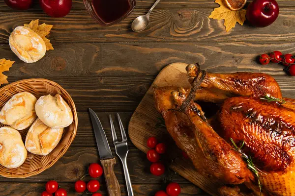stock image thanksgiving turkey and freshly baked buns near cherry tomatoes and cutlery on rustic wooden table