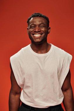 Mutlu ve sportif Afro-Amerikan beyaz atletli adam kırmızı, modern erkek modelde kameraya gülümsüyor.