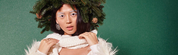 зимняя красота, женщина с белым макияжем и естественным венком регулируя шарф под падающим снегом, баннер