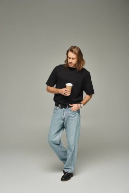 Uzun saçlı, sakallı, elinde kahve bardağıyla gezen yakışıklı bir adam.