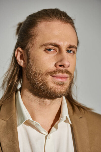 портрет симпатичного бизнесмена в рубашке и бежевом пиджаке на сером фоне, посмотрите в камеру