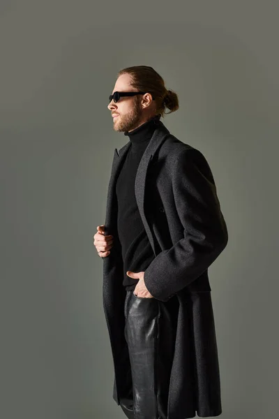 stock image portrait of handsome male model in trendy sunglasses and black attire posing with hand in pocket