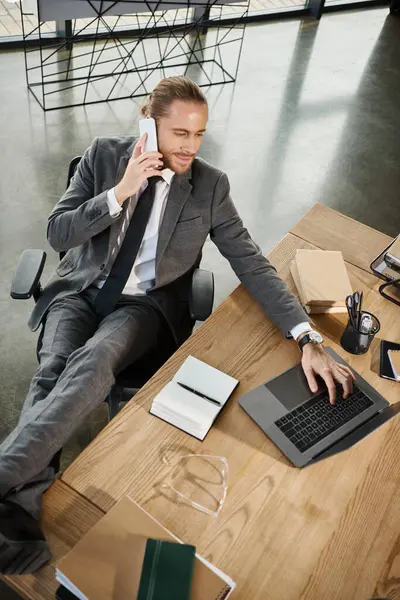top view of ambitious businessman using laptop and sitting with legs on work desk in office
