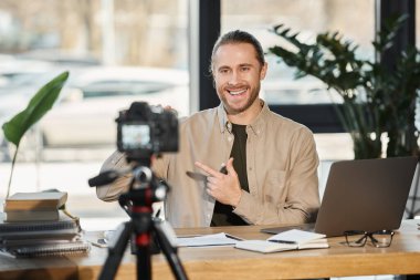 gülümseyen işadamı dijital kamera önünde konuşuyor ve modern ofiste video içeriği kaydediyor