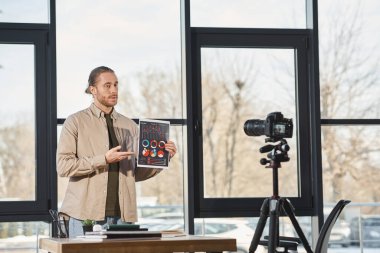 Girişimci ofisteki dijital kamerada video günlüğü sırasında belgeyi bilgi grafikleriyle birlikte gösteriyor