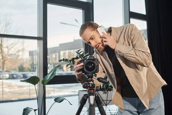 бизнесмен разговаривает на смартфоне рядом с профессиональной цифровой камерой в офисе, видео блоггер