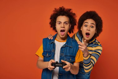 loving african american brother and sister playing video games with joystick, family concept clipart
